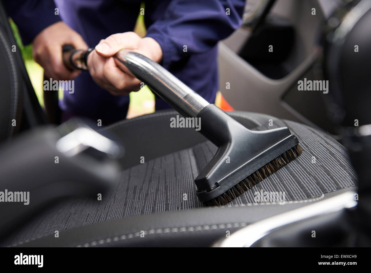 L'uomo Hoovering sedile della vettura durante la pulizia dell'auto Foto Stock