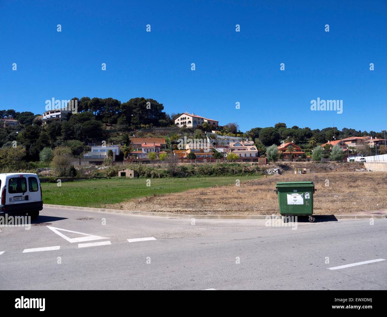 Il contenitore di riciclaggio su ruote al centro della strada, con belle case in background sulla collina Foto Stock