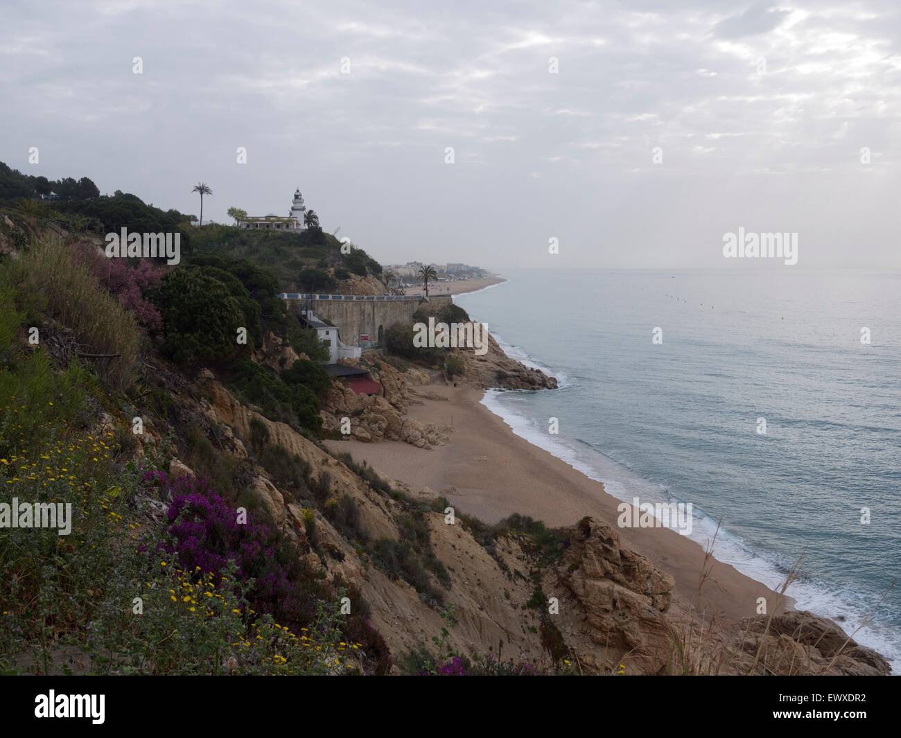 Spiaggia vuota in Spagna in un cupo guardando al giorno con un faro affacciato sulla scogliera Foto Stock