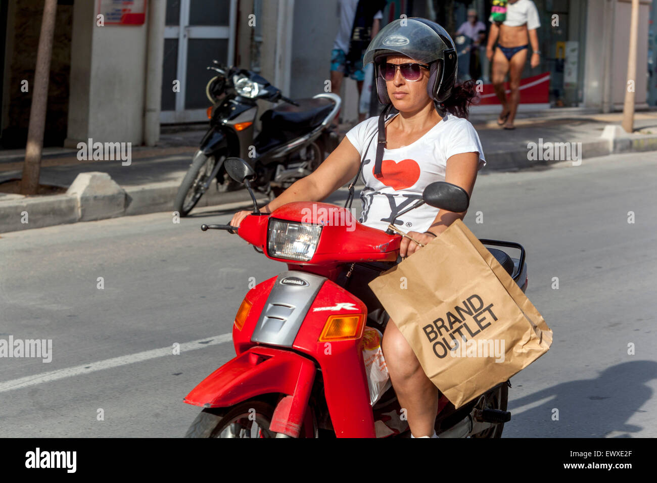 Via di Rethymno donna con una borsa per la spesa va su uno scooter, Creta, Grecia, Grecia, Europa economica scooter donna Foto Stock