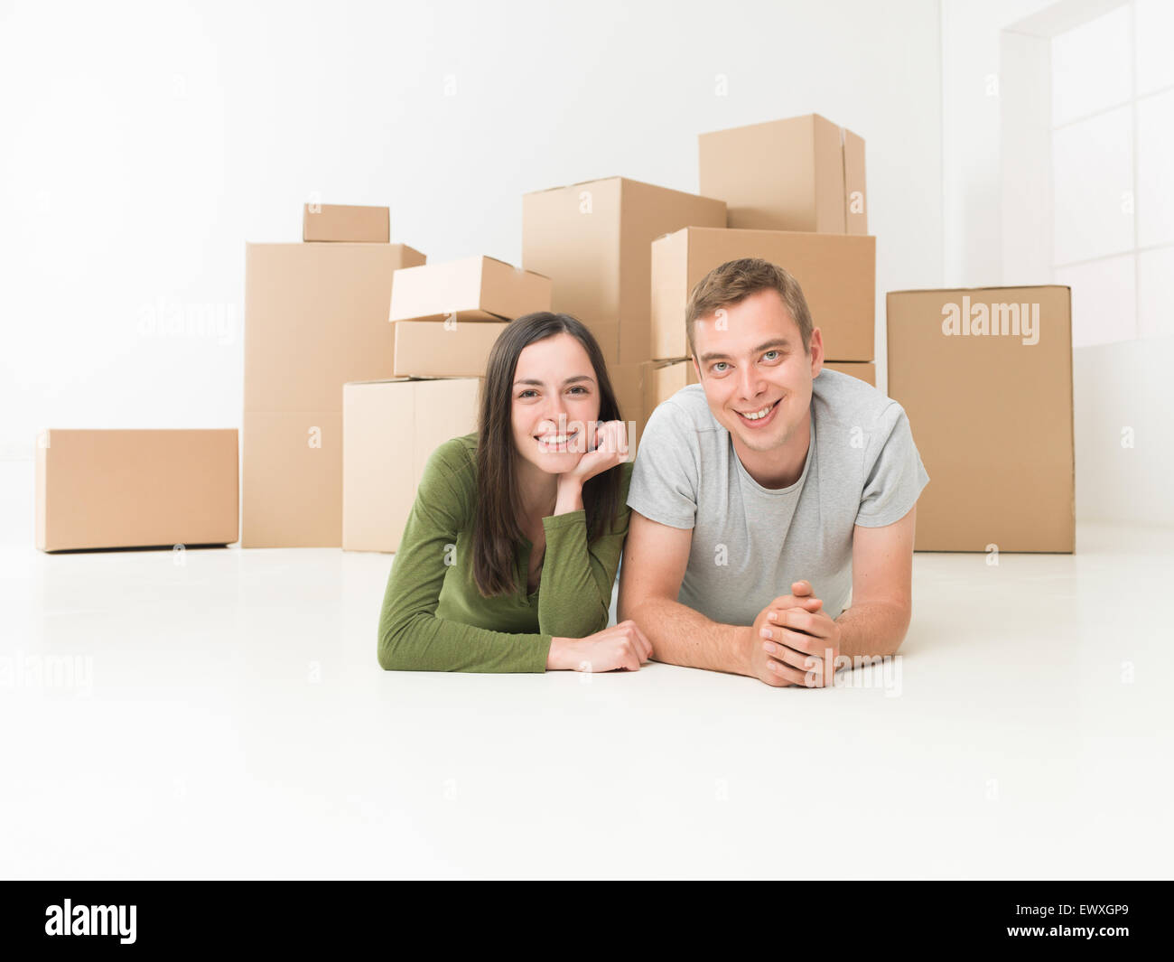 Felice coppia giovane seduto sul pavimento nella loro nuova casa Foto Stock