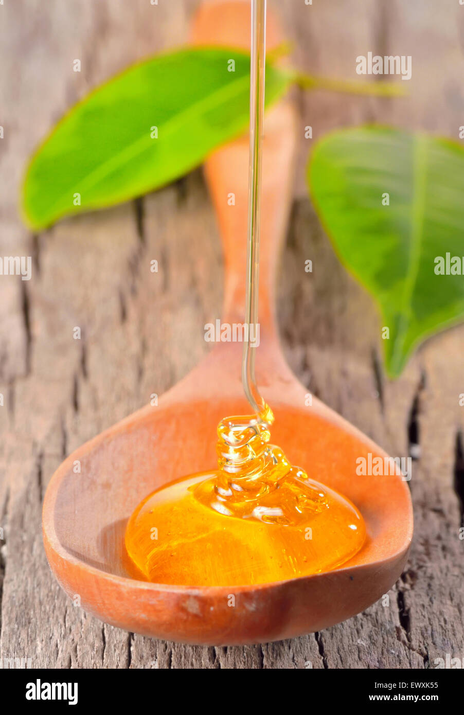 Il miele che cade su di un cucchiaio isolati su legno vecchio Foto Stock