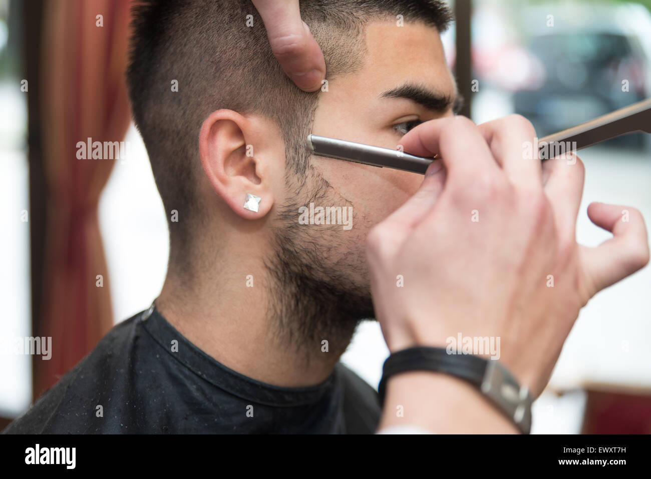 Bel giovane parrucchiere dando un nuovo taglio di capelli al cliente maschio a salottino Foto Stock