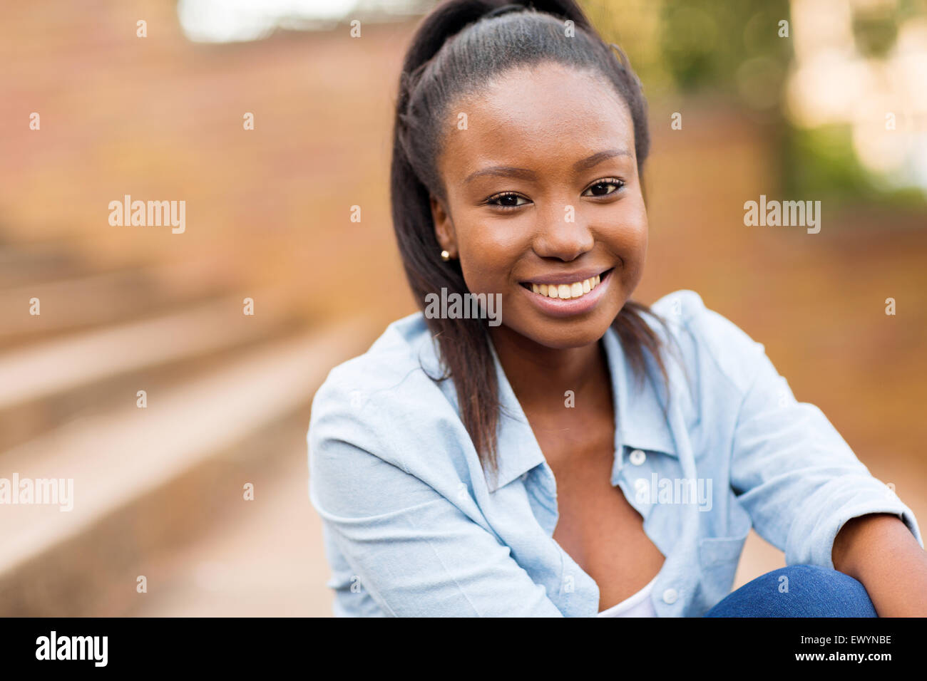 Ritratto di African American femmina studente universitario seduti all'aperto Foto Stock