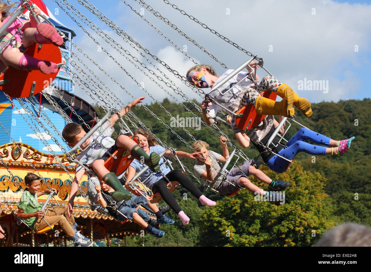 Bambini ride su una tradizionale giostra di oscillazione alla fiera vintage a Chatsworth Country Fair Peak District DERBYSHIRE REGNO UNITO Foto Stock