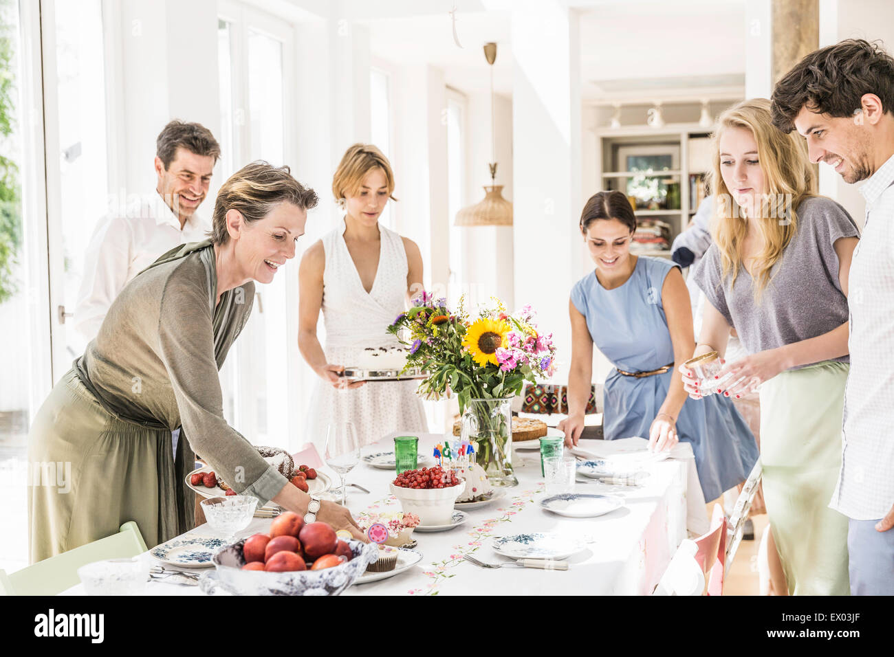 Il team di famiglia posa tavolo da pranzo per party Foto Stock