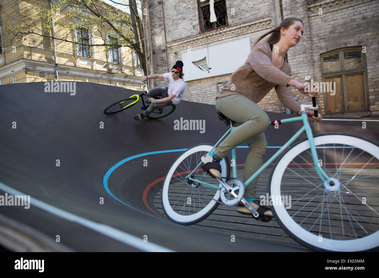 Maschio e femmina di ciclisti racing in discesa sulla città velodromo, Riga, Lettonia Foto Stock