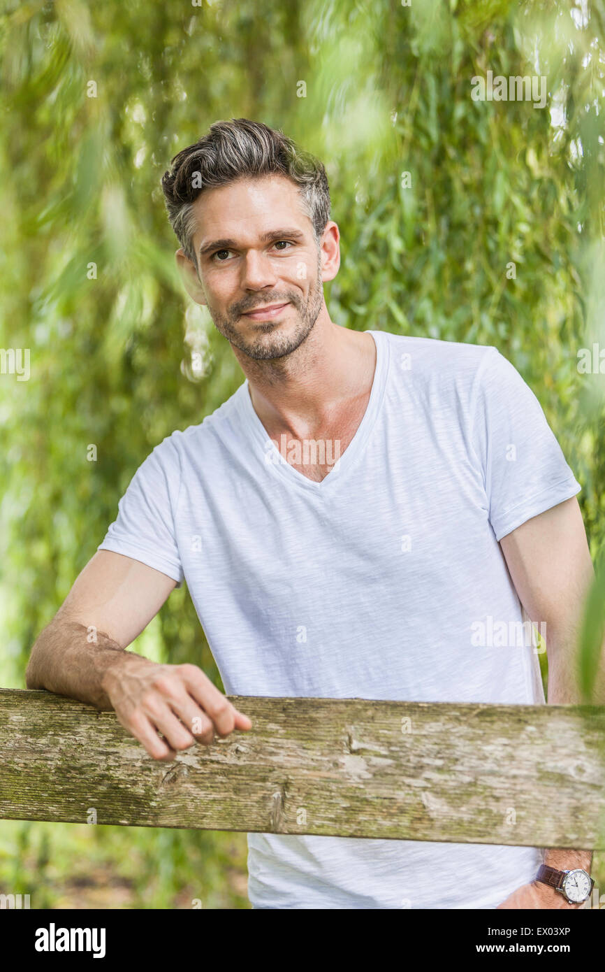 Ritratto di metà uomo adulto appoggiata sulla recinzione in foresta Foto Stock