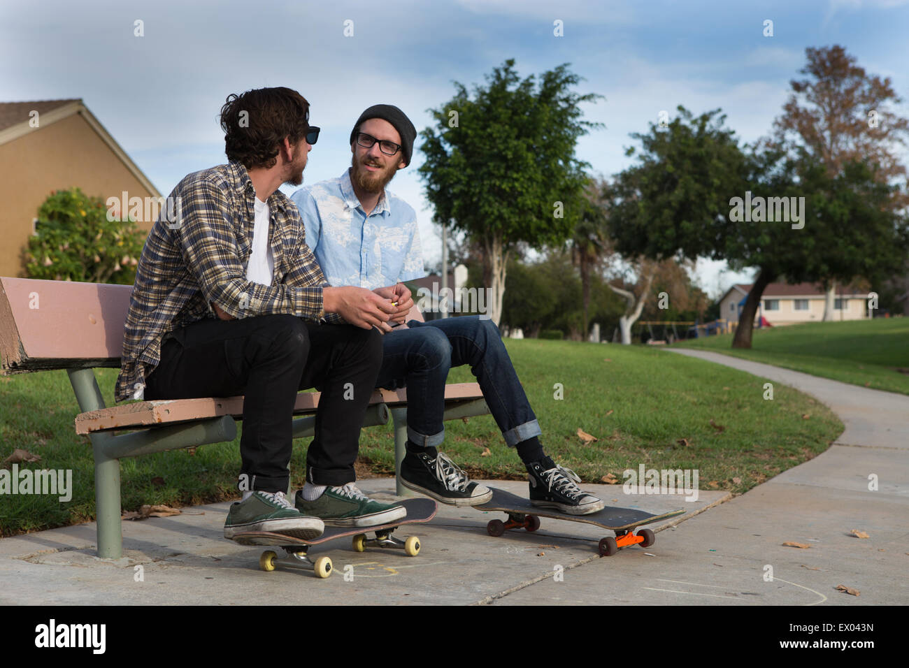 Due giovani skateboarders maschio chattare su banco suburbana Foto Stock