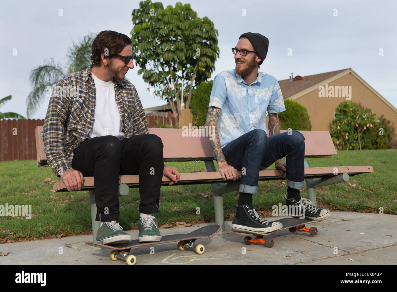 Due giovani skateboarders maschio seduta sul banco suburbana Foto Stock