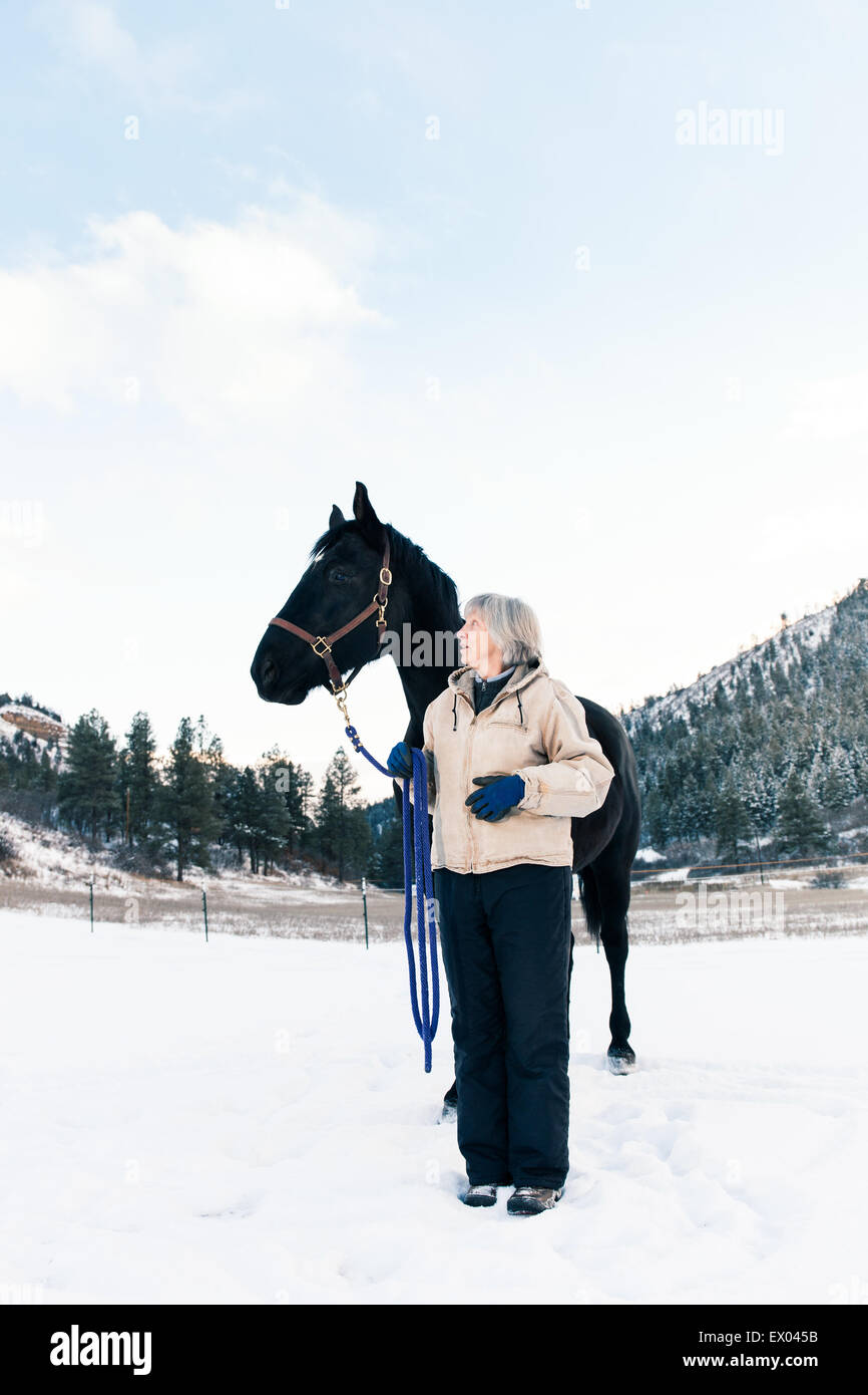 Senior adulto donna con cavallo nel paesaggio innevato Foto Stock