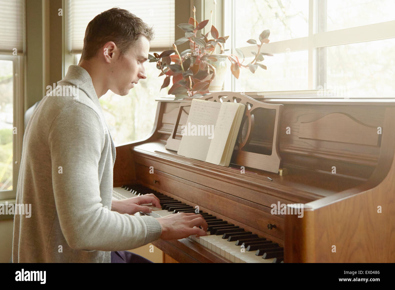 Giovane uomo suonare il pianoforte in salotto Foto Stock