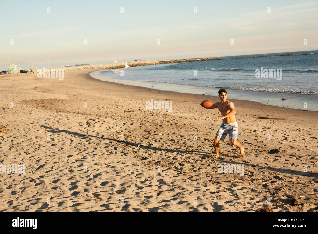 Giovane uomo gettando la sfera sulla spiaggia Foto Stock