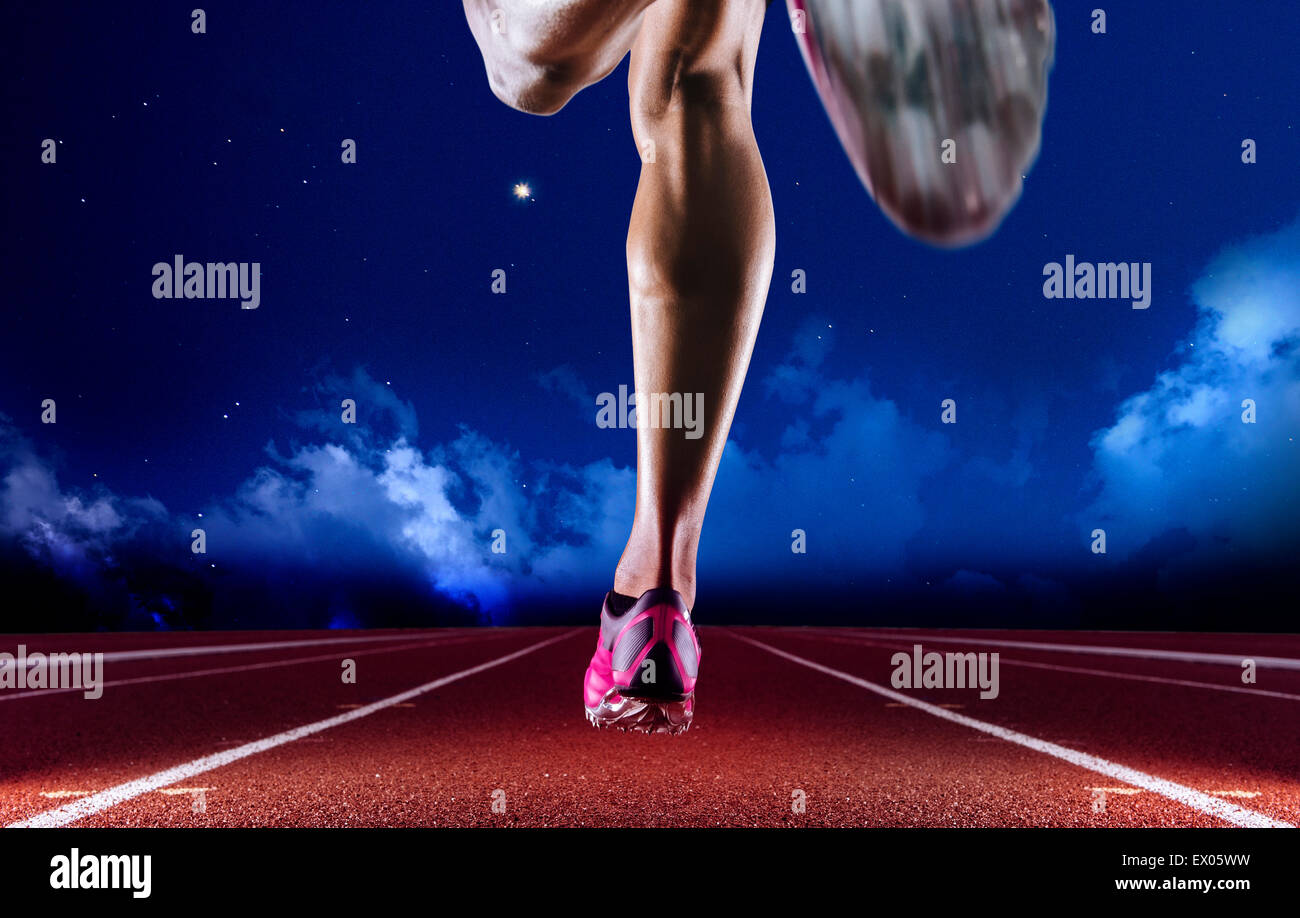 Gambe di giovani femmine atleta che corre sulla pista di notte Foto Stock