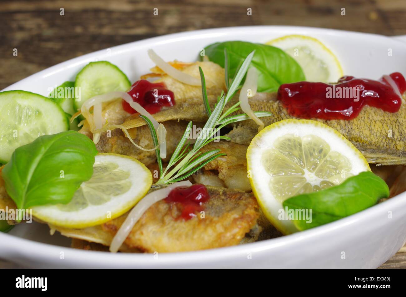 Pesci fritti con basilico sulla piastra bianca Foto Stock