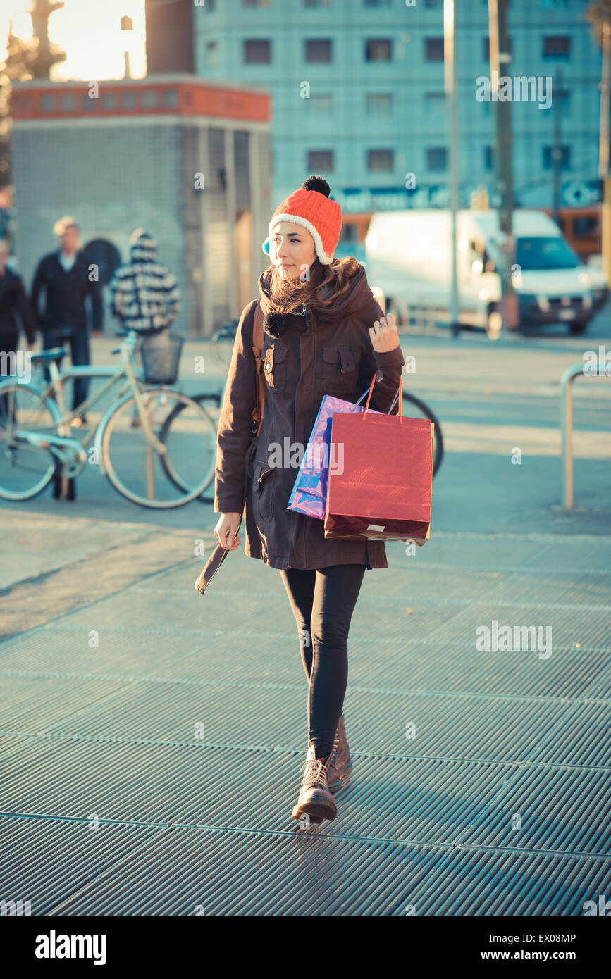 Metà donna adulta indossando red pom pom hat passeggiando con borse per lo shopping Foto Stock