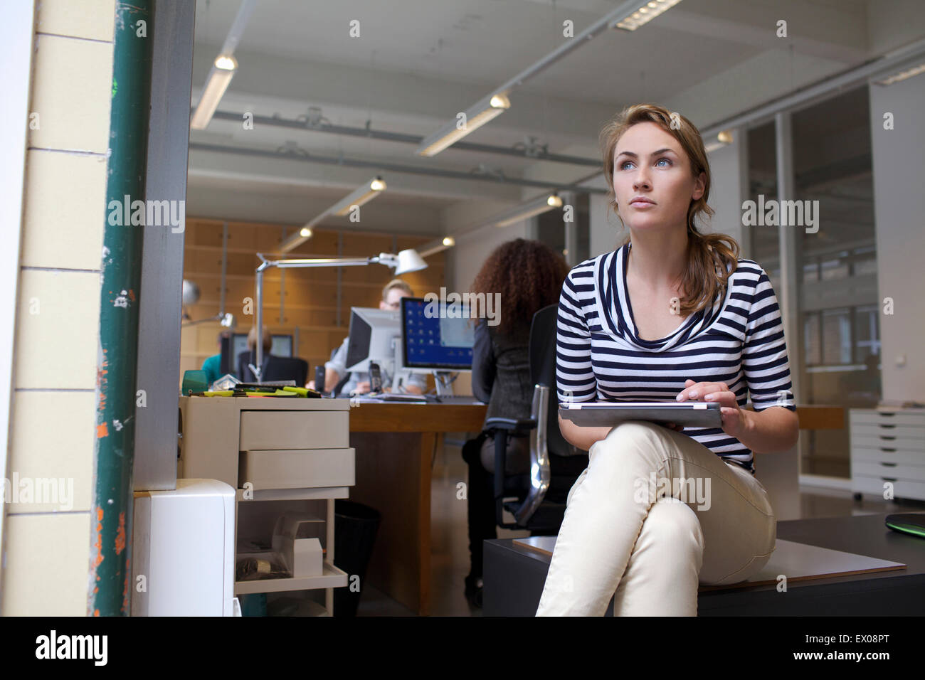 Giovane donna con tavoletta digitale in ufficio Foto Stock