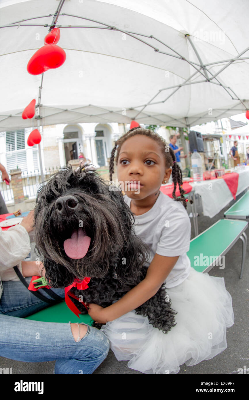 Un po' di nero ragazza abbracci un cane che ha appena vinto un premio in un partito di strada cane la concorrenza Foto Stock