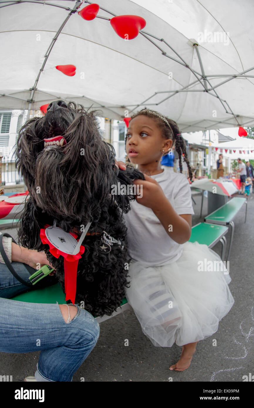 Un po' di nero ragazza abbracci un cane che ha appena vinto un premio in un partito di strada cane la concorrenza Foto Stock