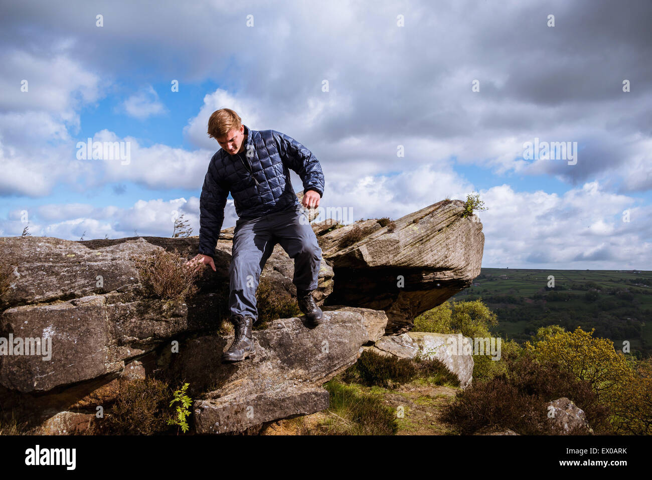 Maschio escursionista teenage scendendo le rocce su pretesto Cliff, ponte Pateley, Nidderdale, Yorkshire Dales Foto Stock