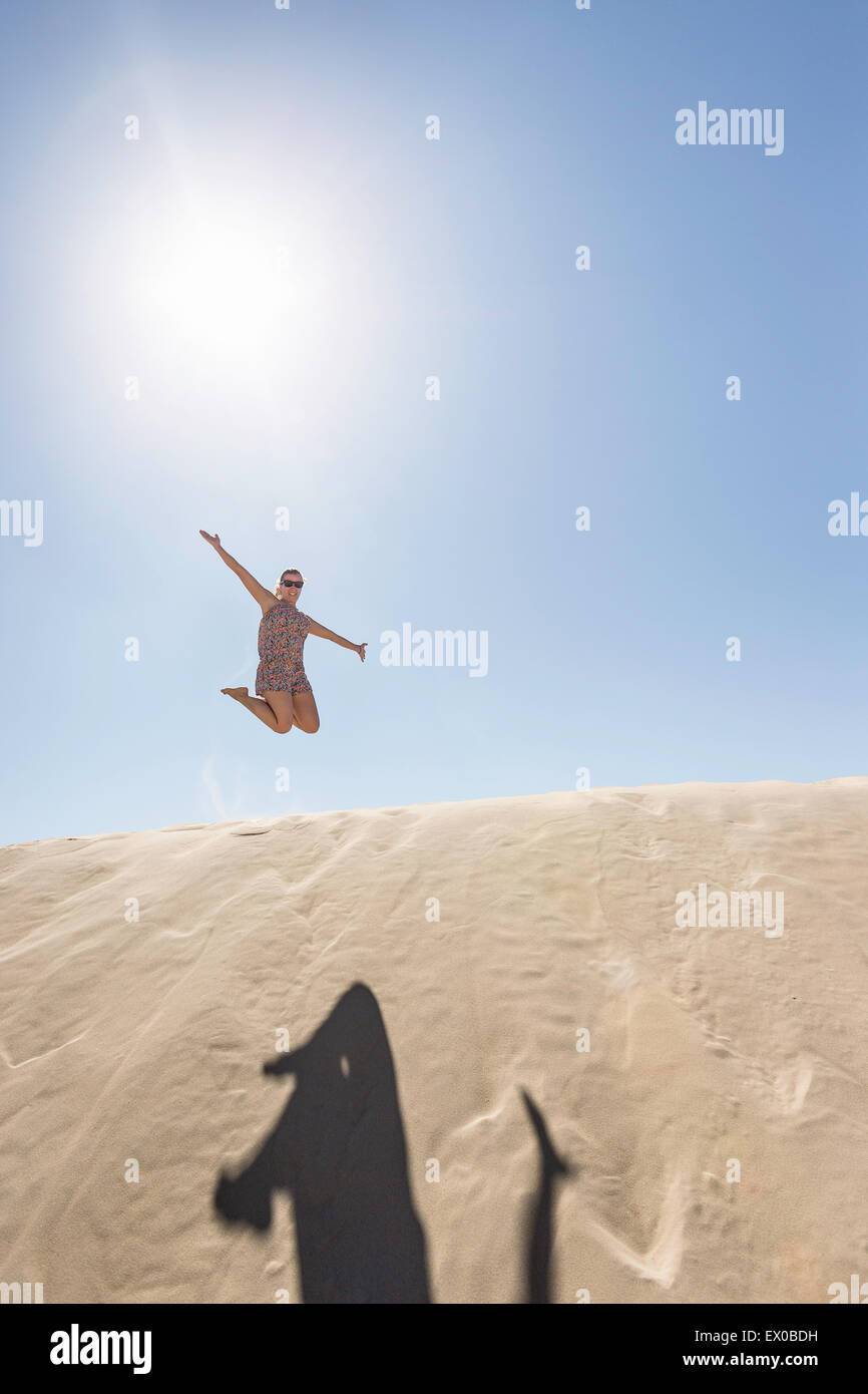 Giovane donna jumping metà aria, Dune de Pilat, Francia Foto Stock