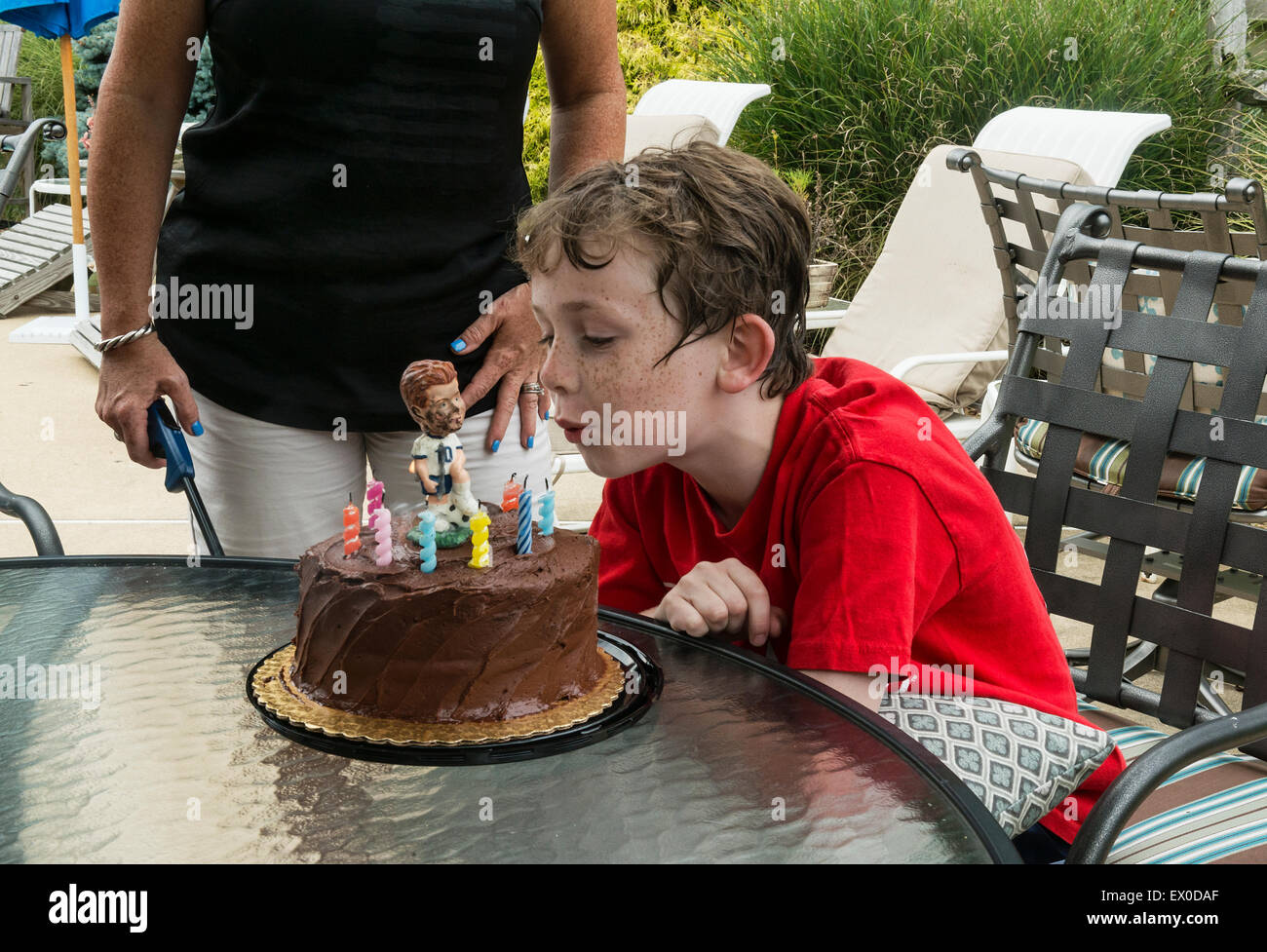 Il ragazzo si brucia le candele su una torta di compleanno adornata con un giocatore di calcio figura. Foto Stock