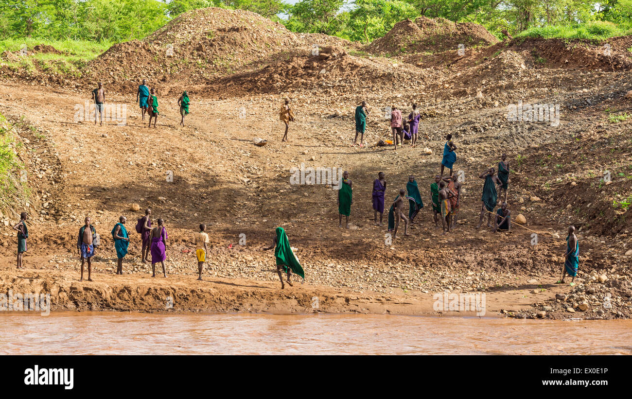 Membri della tribù africana Suri in piedi sulle rive di un fiume Foto Stock