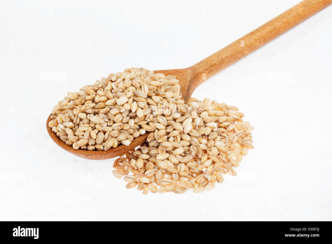 Il cucchiaio di legno con orzo perlato , su sfondo bianco Foto Stock