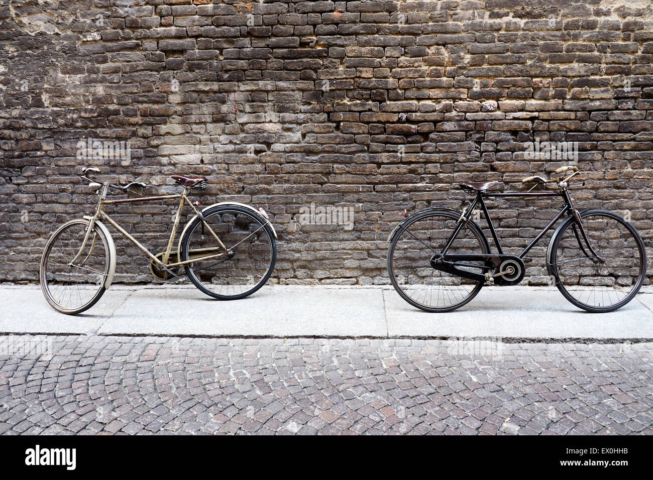 Due biciclette vintage in appoggio contro un muro di mattoni. Foto Stock