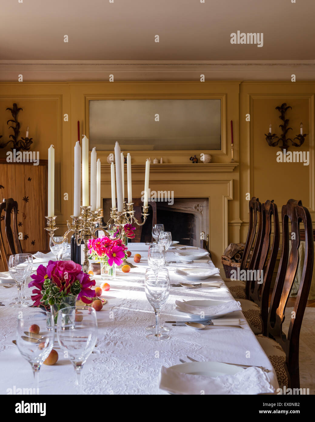 Candelabri sul tavolo da pranzo con il bianco tovaglia in cotone e antichi sedie da pranzo Foto Stock