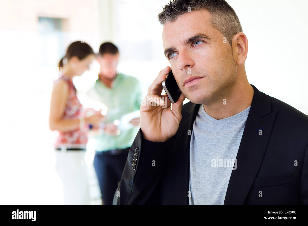 Ritratto di imprenditore parlando al telefono cellulare in ufficio. Foto Stock
