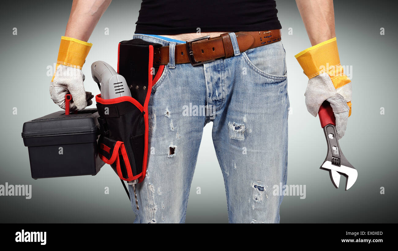 Repairman holding toolbelt e chiave su sfondo grigio Foto Stock
