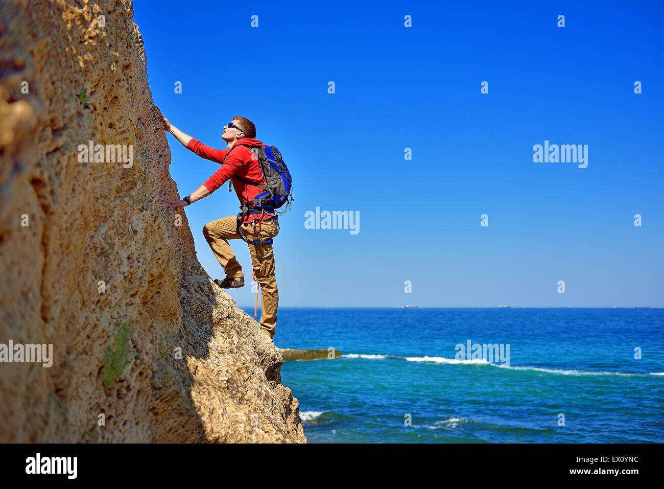 Giovane uomo salire la roccia su sfondo del mare Foto Stock