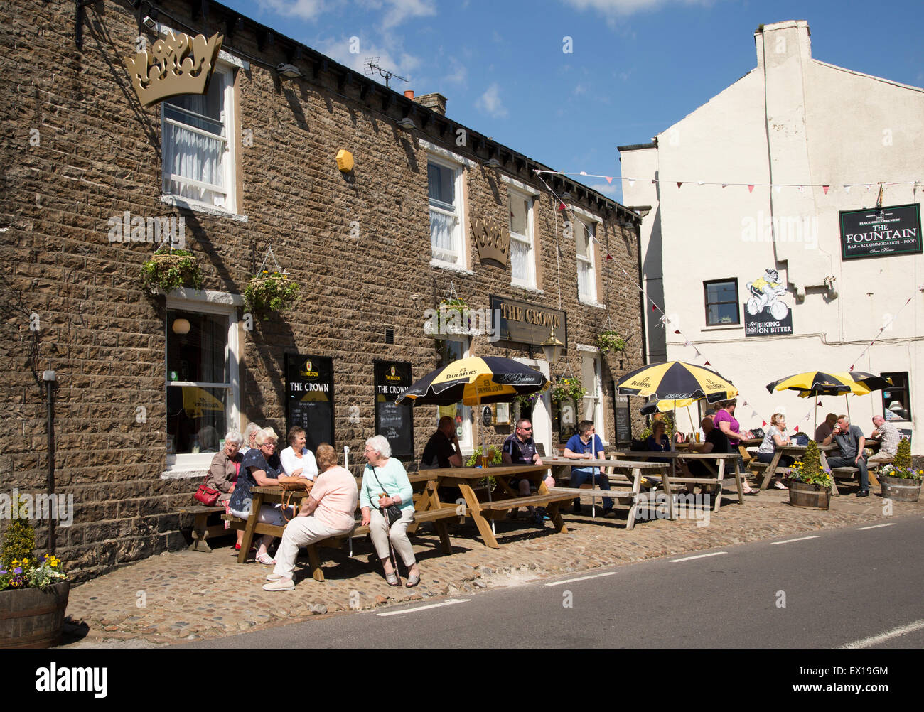 La gente seduta al di fuori del pub nel villaggio di Hawes, Yorkshire Dales National Park, England, Regno Unito Foto Stock