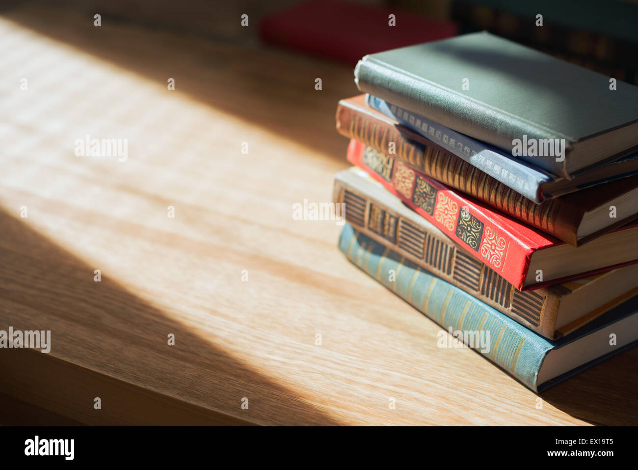I libri sul tavolo di fronte alla luce del sole. Profondità di campo. Foto Stock