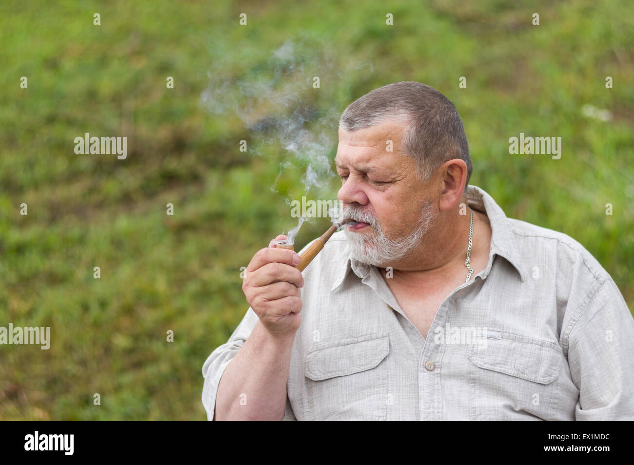 Outdoor ritratto di un uomo anziano di tabacco da fumo-pipe Foto Stock