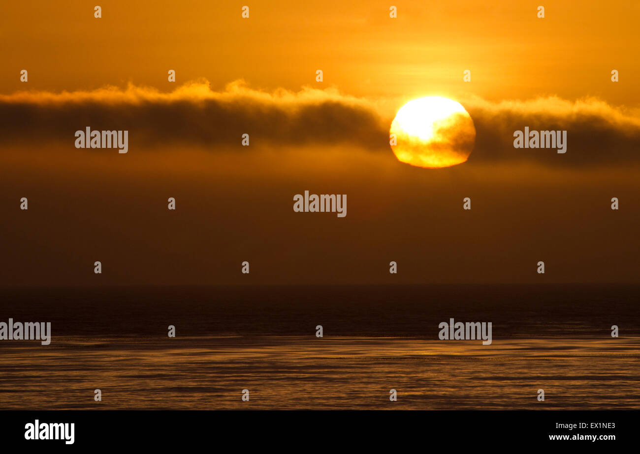 Tramonto dietro una nuvola sull'Oceano Pacifico Foto Stock