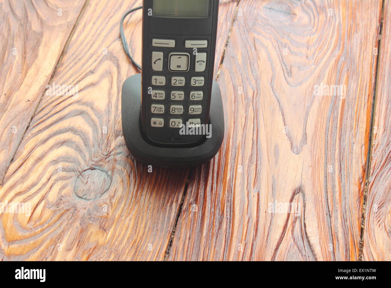 Su una tavola di legno è un telefono cordless sulla base di ricarica Foto Stock