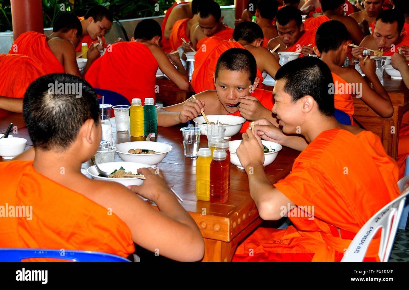 Chiang Mai, Thailandia: giovani monaci buddisti in arancione wrap-around accappatoi di mangiare il pranzo in Wat Suan Dok sala da pranzo Foto Stock