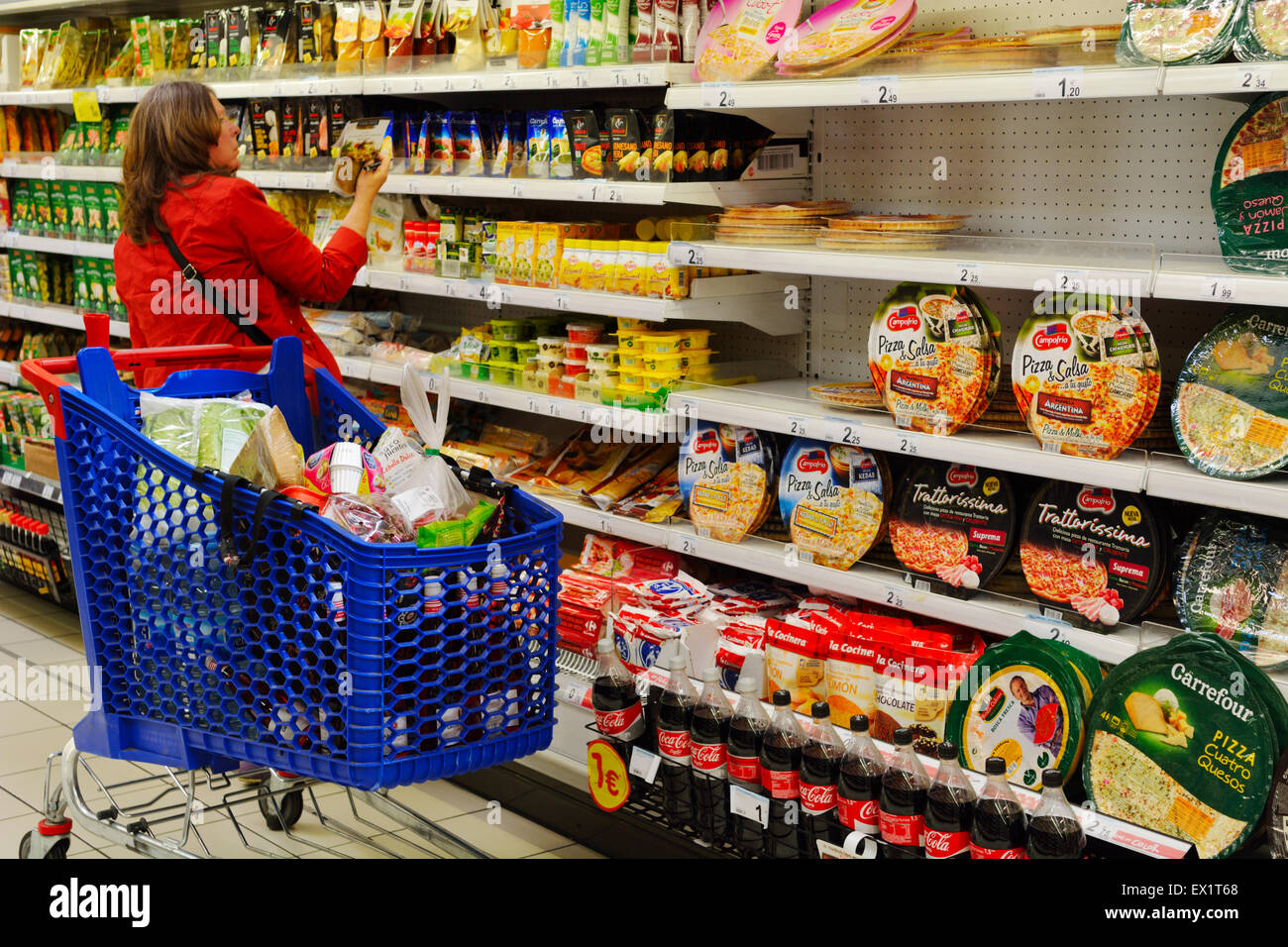 Donna shopping nel supermercato che ripiani di pizza e altri alimenti confezionati Foto Stock