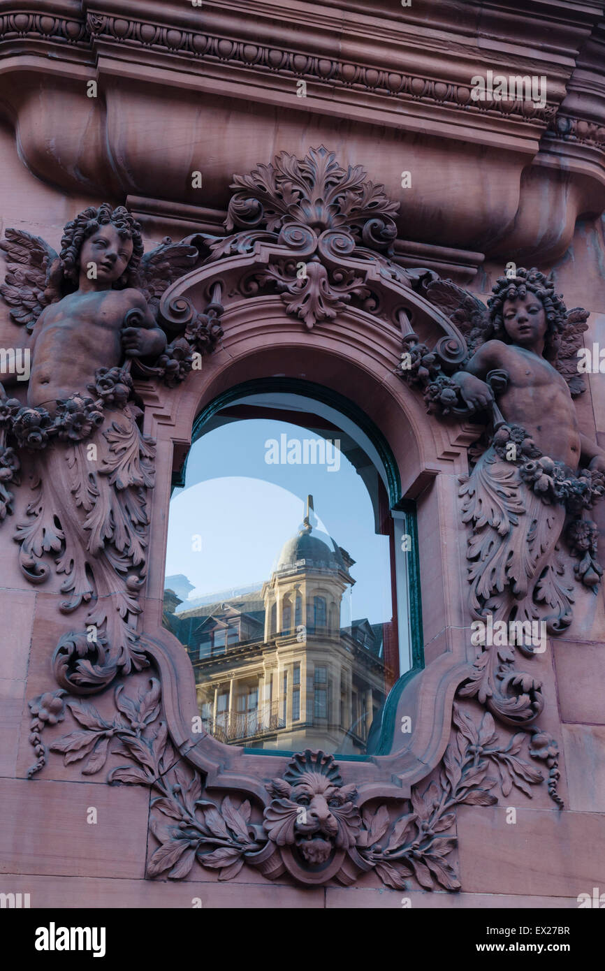 Un Edwardian pietra intagliata medaglione di angeli riflette un edificio adibito a magazzino dello stesso periodo in Manchester, UK. Foto Stock