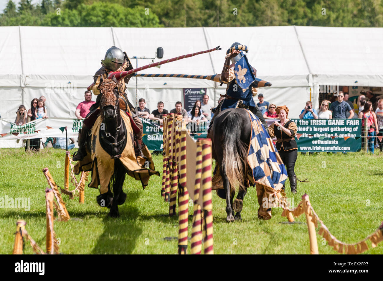 Uomini vestiti come cavalieri dello stadio a giostre battaglia per una folla a una fiera all'aperto. Foto Stock