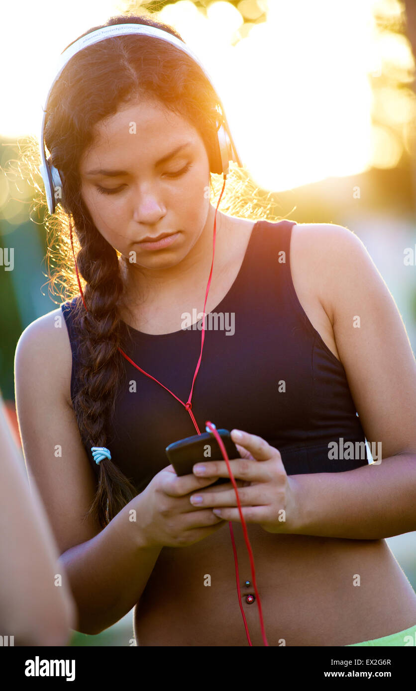 Outdoor Ritratto di giovane ragazza ascoltando la musica con il telefono cellulare. Foto Stock