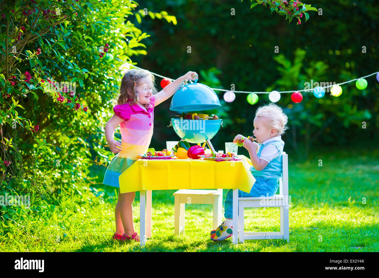 Bambini cuocere carne. Camping Famiglia e godendo di barbecue. Fratello e Sorella a barbecue la preparazione di bistecche e salsicce. Foto Stock