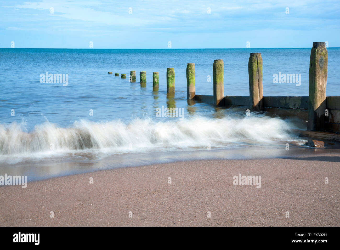 Le difese costiere e lavaggio onde sulla spiaggia a Teignmouth Beach, Devon, Inghilterra Foto Stock