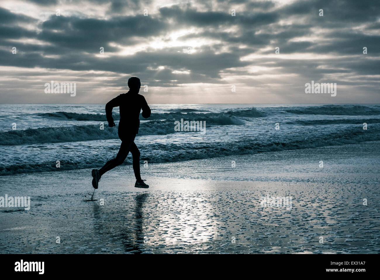 Jogging sulla spiaggia al tramonto Foto Stock