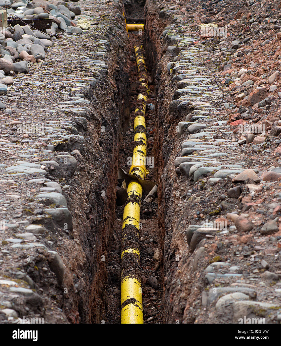 Servizi di Metropolitana gialla polietilene Gas tubo essendo affondato nel terreno sotto la linea di gelo. Foto Stock