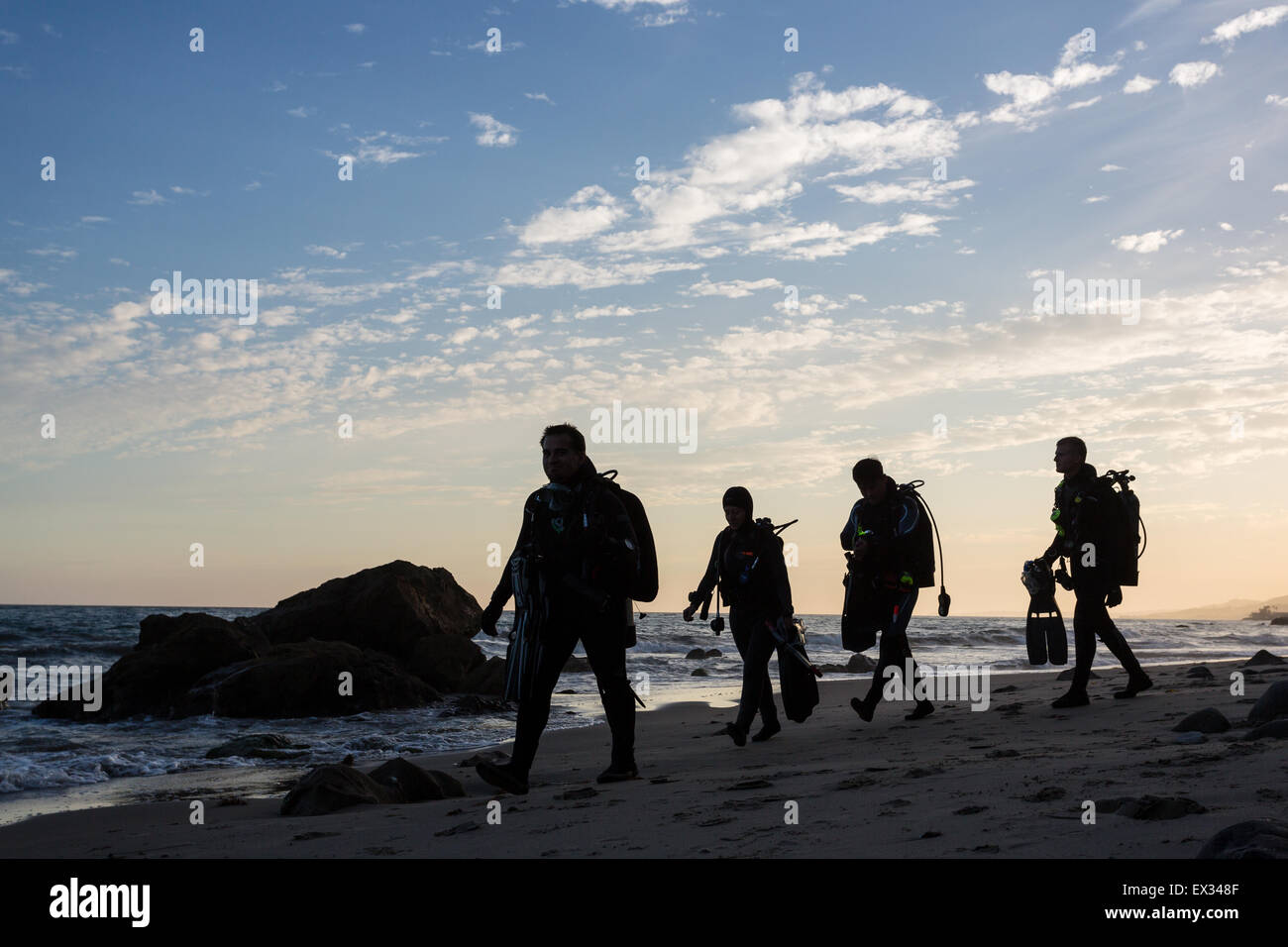 I subacquei a piedi lungo la spiaggia di Malibu appena dopo il tramonto. Foto Stock