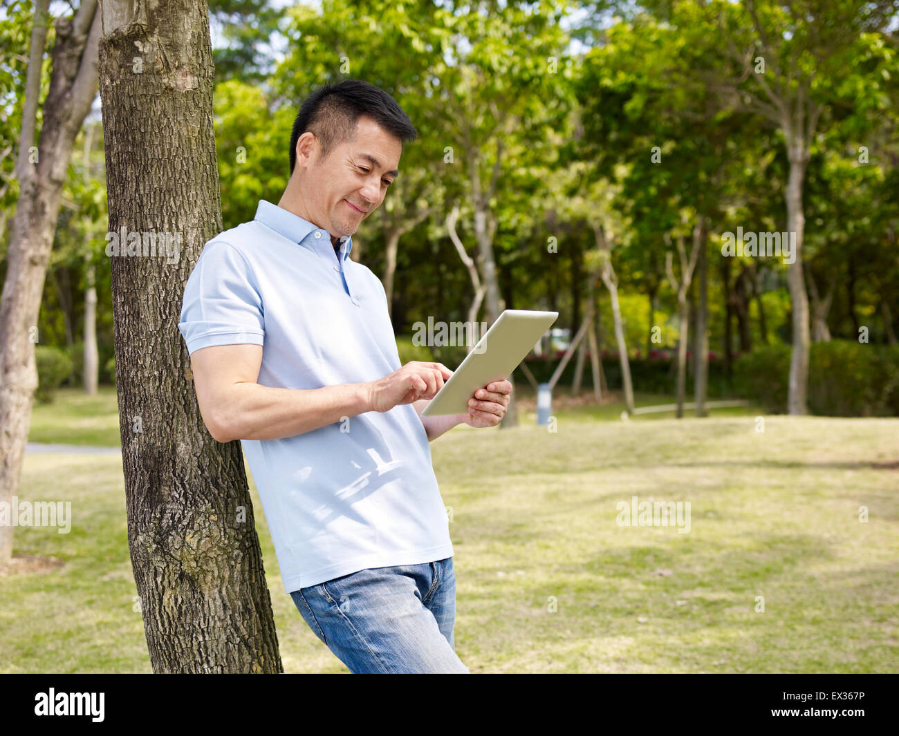 Uomo che utilizza ipad all'aperto in un parco Foto Stock