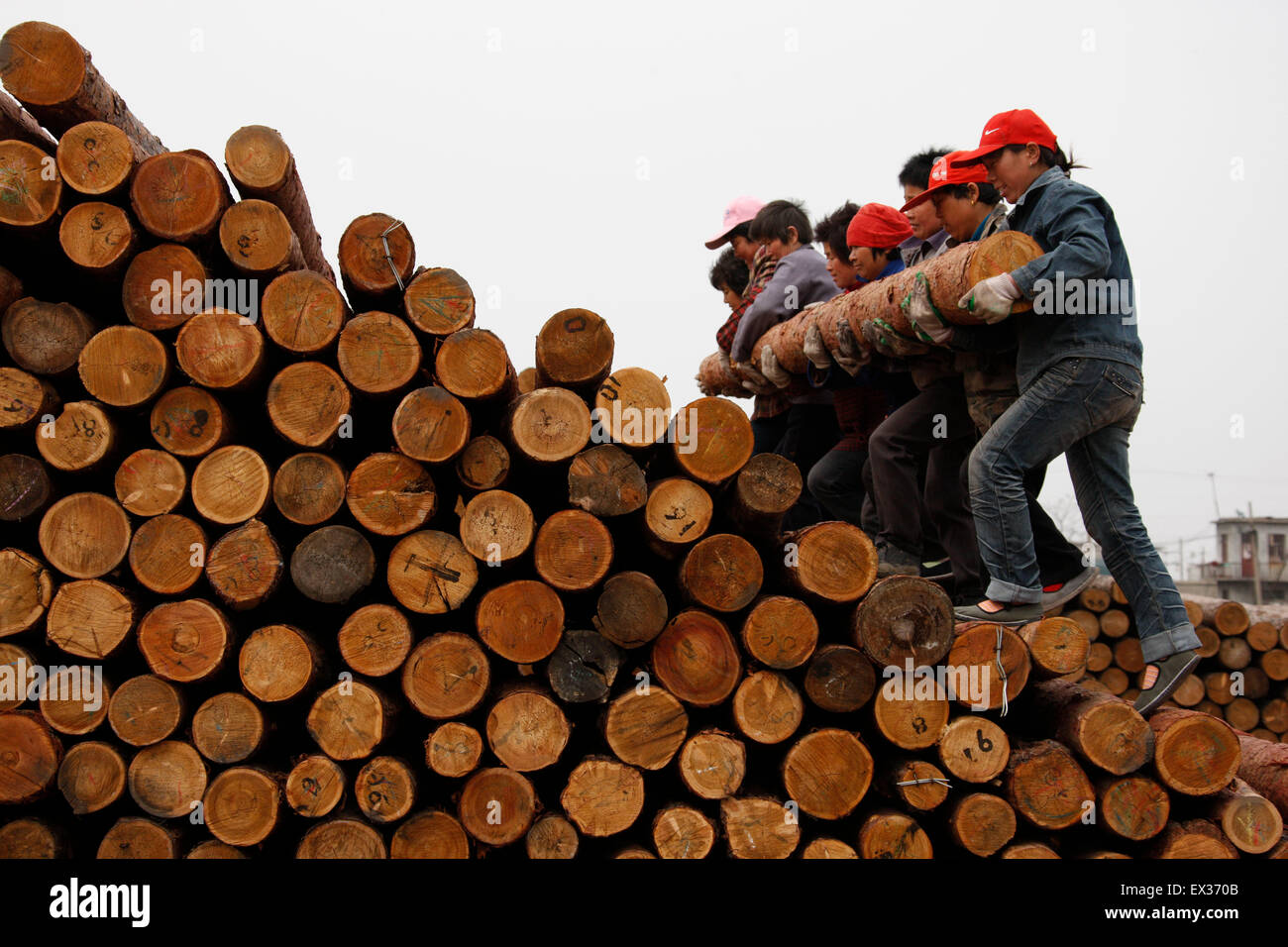Gli operai portano un registro ad un mercato del legname in Huaibei, provincia di Anhui Aprile 6, 2010. VCP Foto Stock